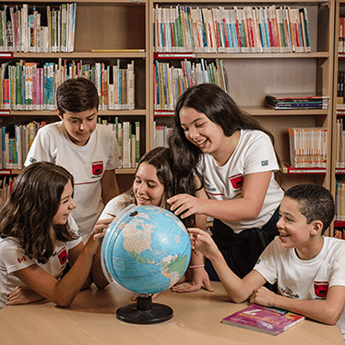 Estudantes do ensino fundamental da MapleBear aprendem nomes de lugares em ingles, no globo terrestre.